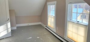 Bedroom with pink walls and concrete floor covered in paint